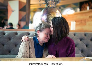 young woman kisses her senior mother