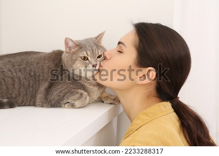 Young woman kissing her adorable cat at home