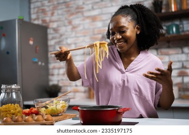 Young woman in kitchen. Beautiful African woman cooking pasta.	 - Powered by Shutterstock