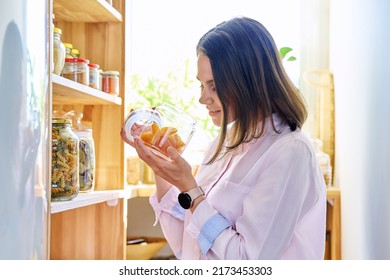 Young Woman In Kitchen With Containers Jars Of Food, With Dried Apricots