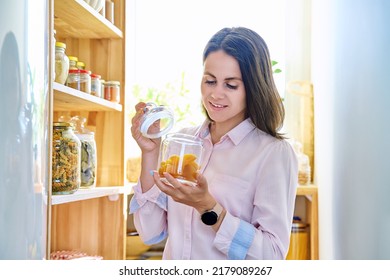 Young Woman In Kitchen With Containers Jars Of Food, With Dried Apricots