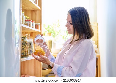 Young Woman In Kitchen With Containers Jars Of Food, With Dried Apricots