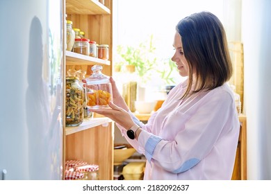 Young Woman In Kitchen With Containers Jars Of Food, With Dried Apricots