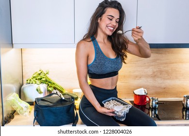 Young Woman In The Kitchen Having Healthy Breakfast. Young Woman Is Resting And Eating A Healthy Meal After A Workout. Fitness And Healthy Lifestyle Concept.