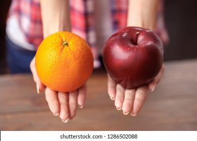 Young woman at kitchen healthy lifestyle standing holding apple and orange shoosing option close-up