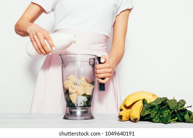 Young Woman In The Kitchen Pours Kefir For Smoothies From Banana And Spinach, Close-up