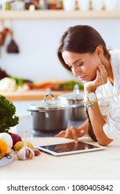 Young woman in the kitchen, using her ipad. Young woman