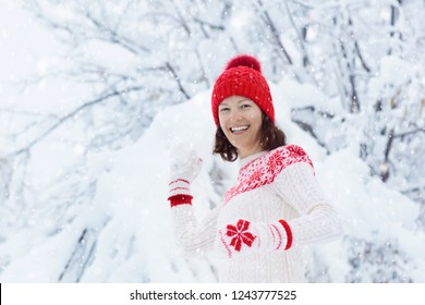 Young Woman In Knitted Sweater Playing Snow Ball Fight In Winter. Girl In Family Snow Balls Game. Female In Knit Handmade Hat And Mittens With Christmas Snowflake Design Having Fun In Snowy Park.