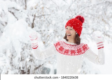 Young Woman In Knitted Sweater Playing Snow Ball Fight In Winter. Girl In Family Snow Balls Game. Female In Knit Handmade Hat And Mittens With Christmas Snowflake Design Having Fun In Snowy Park.