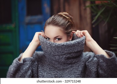 Young woman in a knitted turtleneck sweater covering her face. Close up - Powered by Shutterstock