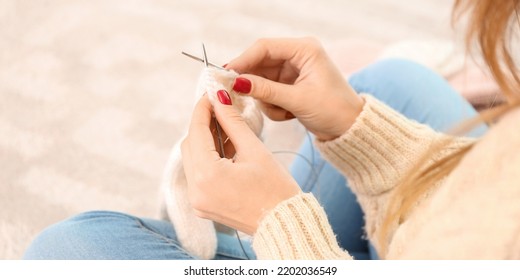 Young Woman Knitting Warm Mittens At Home, Closeup