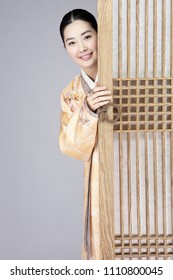 Young Woman In Korean Traditional Clothing Hiding Behind Door