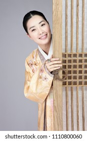 Young Woman In Korean Traditional Clothing Hiding Behind Door