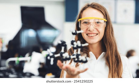 Young woman in a lab holding a molecular model. Science, lab, and molecular model are key. Smiling, wearing safety goggles, engaged in science. Education, knowledge, and science. - Powered by Shutterstock