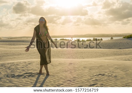Young woman landing on the sand dunes of Mangue Seco beach located in Bahia.