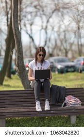 A Young Woman With A Lap Top On A Bench In A City Park.