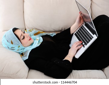 Young woman with laptop lying on couch