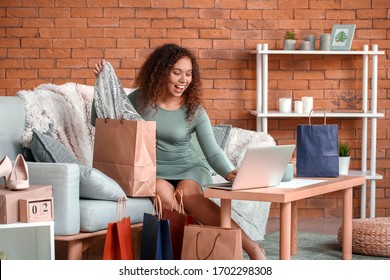 Young Woman With Laptop And New Clothes At Home. Online Shopping Concept