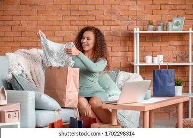 Young Woman With Laptop And New Clothes At Home. Online Shopping Concept