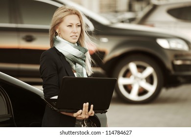 Young woman with laptop on a car parking