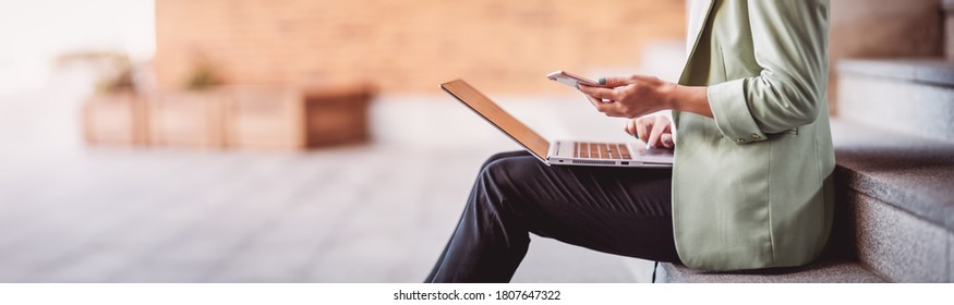 junge Frau mit Laptop, die auf der Treppe sitzt. Person, die im Freien den PC benutzt
