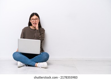 Young Woman With A Laptop Sitting On The Floor Shouting With Mouth Wide Open