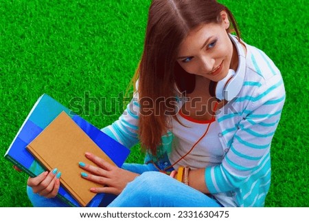 Young woman with laptop sitting on green grass . Portreit young woman