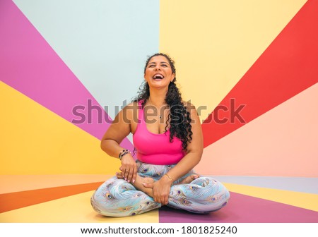 young woman laughing  in a yoga pose in a colorful room