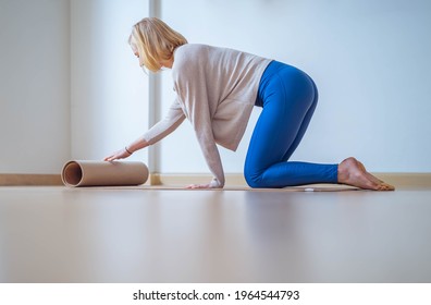 Young Woman Laying Down Mat To Do Yoga At Home.