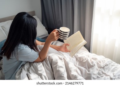 Young woman laying on her cozy bed and making notes to her diary. Fall season mood. Stripe light and shadow.