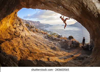 Young Woman Lead Climbing In Cave With Beautiful View In Background 