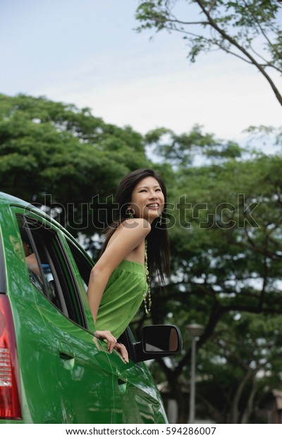 A young\
woman leans out of the window of a\
car