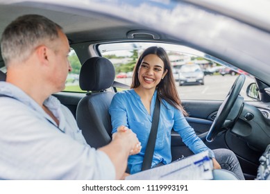 Young woman learning how to drive car together with her instructor. Driving school. Happy driving student.  Woman passed. Young woman delighted having just passed her driving test