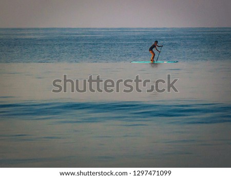 Young woman learning how to paddleboard in the beach in Goa enjoying water sports