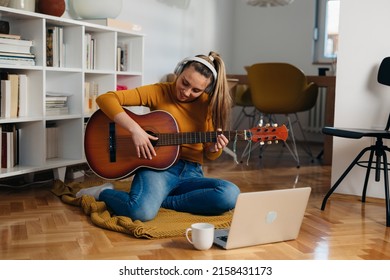 young woman learning to play guitar at home