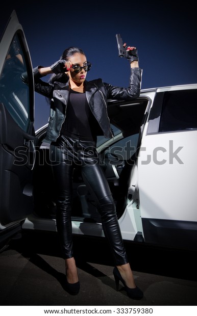 Young woman in leather\
clothes with gun