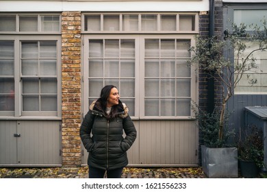 Young Woman Leaving Her House And Using Her Smart Mobile With Colorful Houses On Portobello Street In The Notting Hill Neighborhood