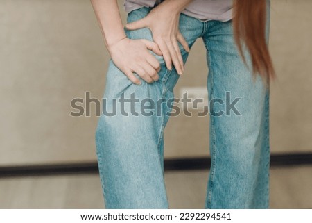 Young woman with leg hip pain ache against brown background
