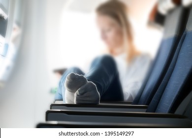 Young Woman With Legs On The Plane Seat. A Passenger Relaxes On A Flying Plane With Her Feet Upstairs.