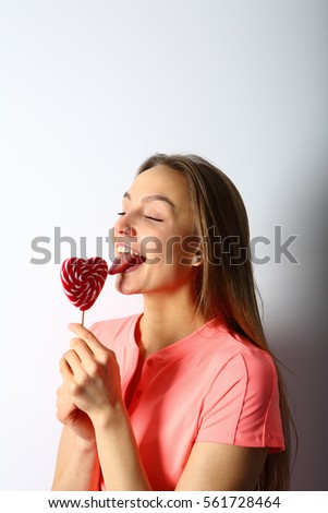 Young woman licking lollipop in valentine's day holiday