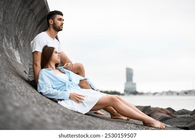 Young woman lies with her head on her man's shoulder on a rocky seashore - Powered by Shutterstock