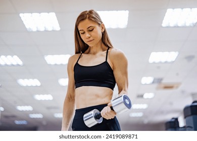 Young woman lifting dumbbells in the gym - Powered by Shutterstock