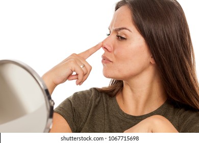 Young woman lifting her nose with her finger on white background