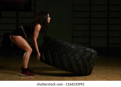 Young Woman Lifting Tire. Girl Work Out With Big Car Tire