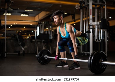 Young Woman Lifting Weights In The Gym