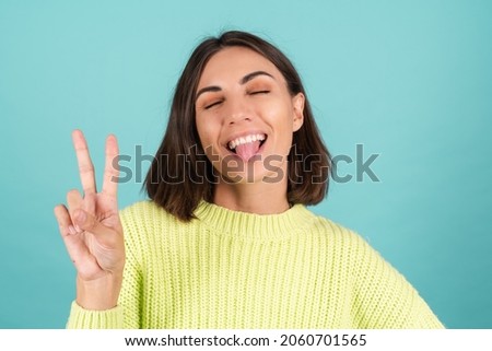 Young woman in light green sweater cute happy smiling shows v sign