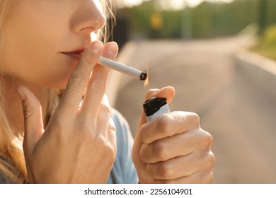 Young woman lighting cigarette outdoors, closeup of hands - Powered by Shutterstock