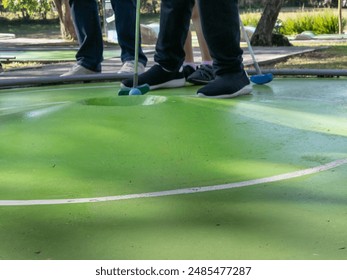 A young woman lines up a putt on a whimsical miniature golf course. - Powered by Shutterstock