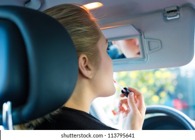 Young Woman With Lipstick In Car Looks Into Review Mirror