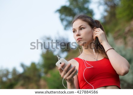 Similar – Woman with earphones listening music in smartphone